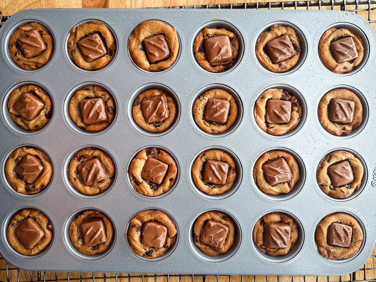 Snickers candy pressed into chocolate chip cookie cups.