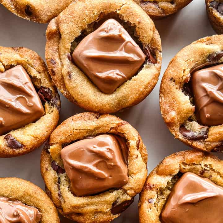 Snickers chocolate chip cookie cups on a plate.