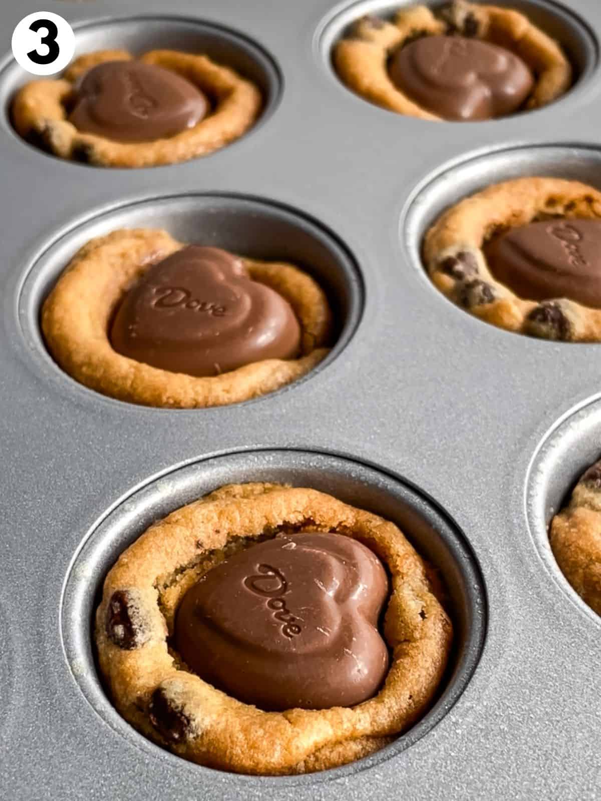 Heart chocolates pressed into chocolate chip cookie cups in the pan.