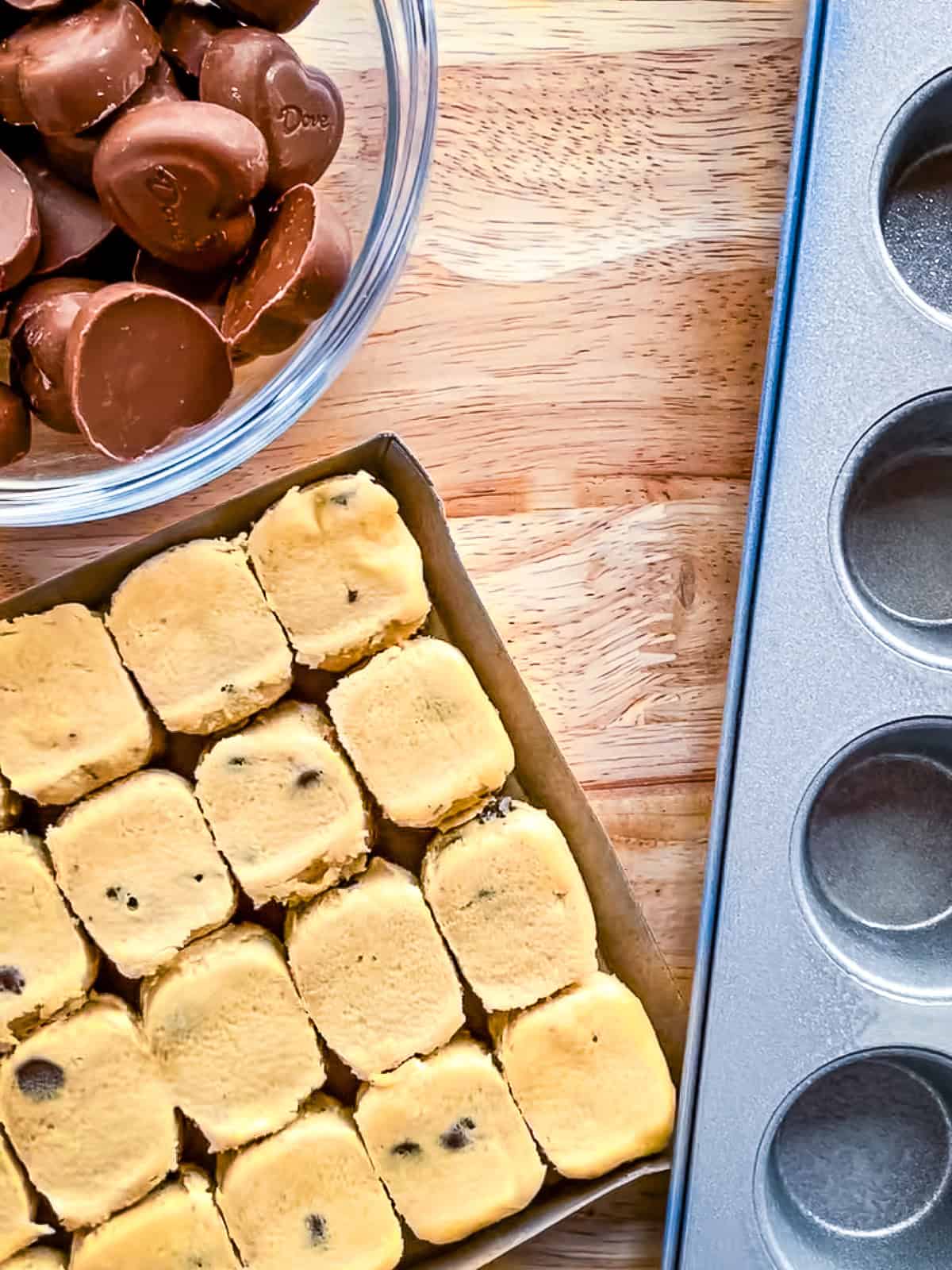 Ingredients for heart cookie cups. Heart chocolates in a bowl. Chocolate chip cookie dough and a mini muffin pan.