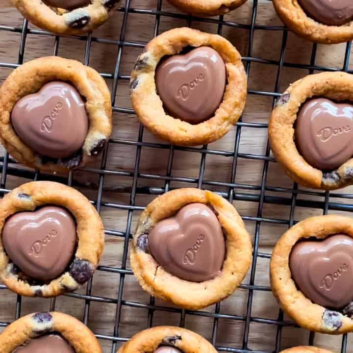 Cookie cups with heart chocolates cooling on a wire rack.