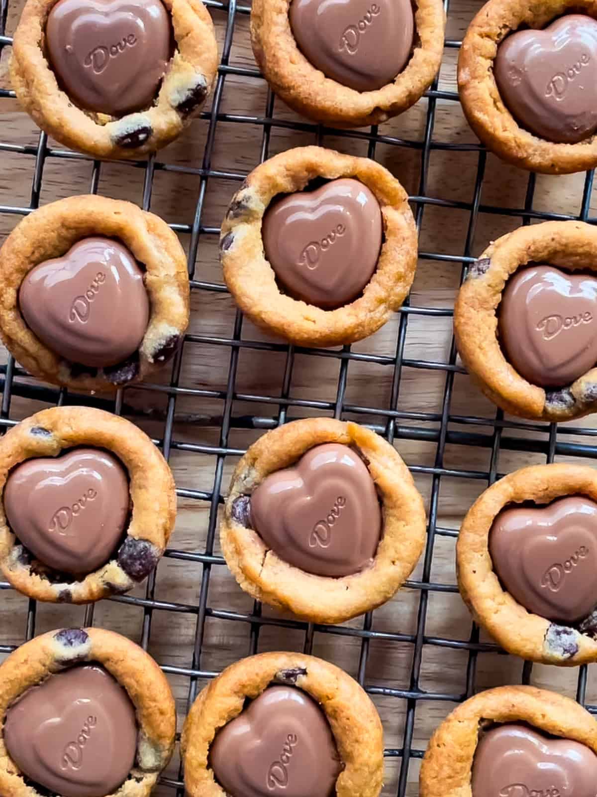 Cookie cups with heart chocolates cooling on a wire rack.