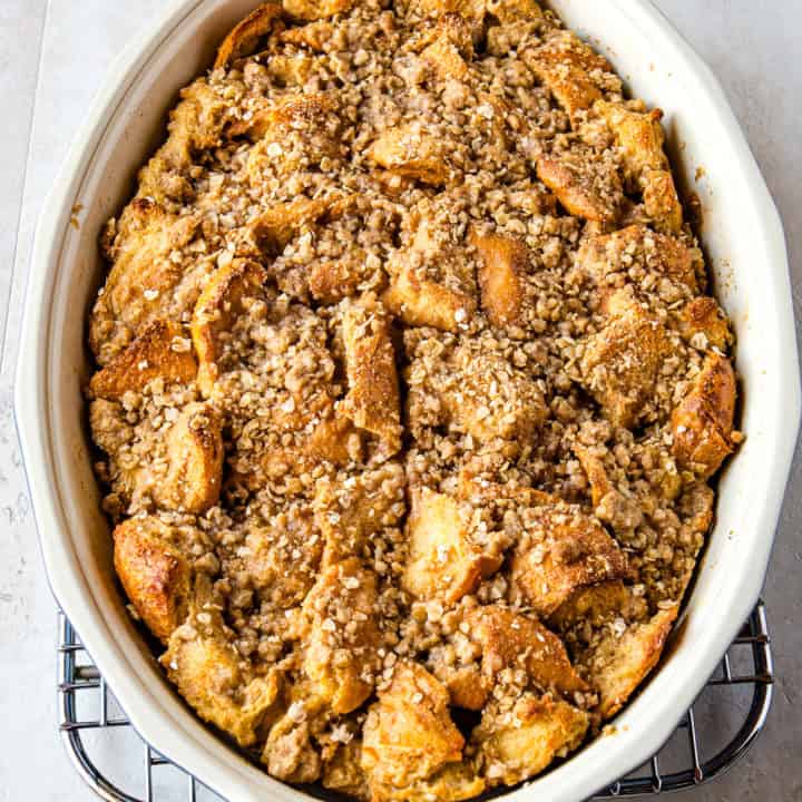 Baked French toast casserole in an oval pan. The casserole is topped with oat streusel topping.