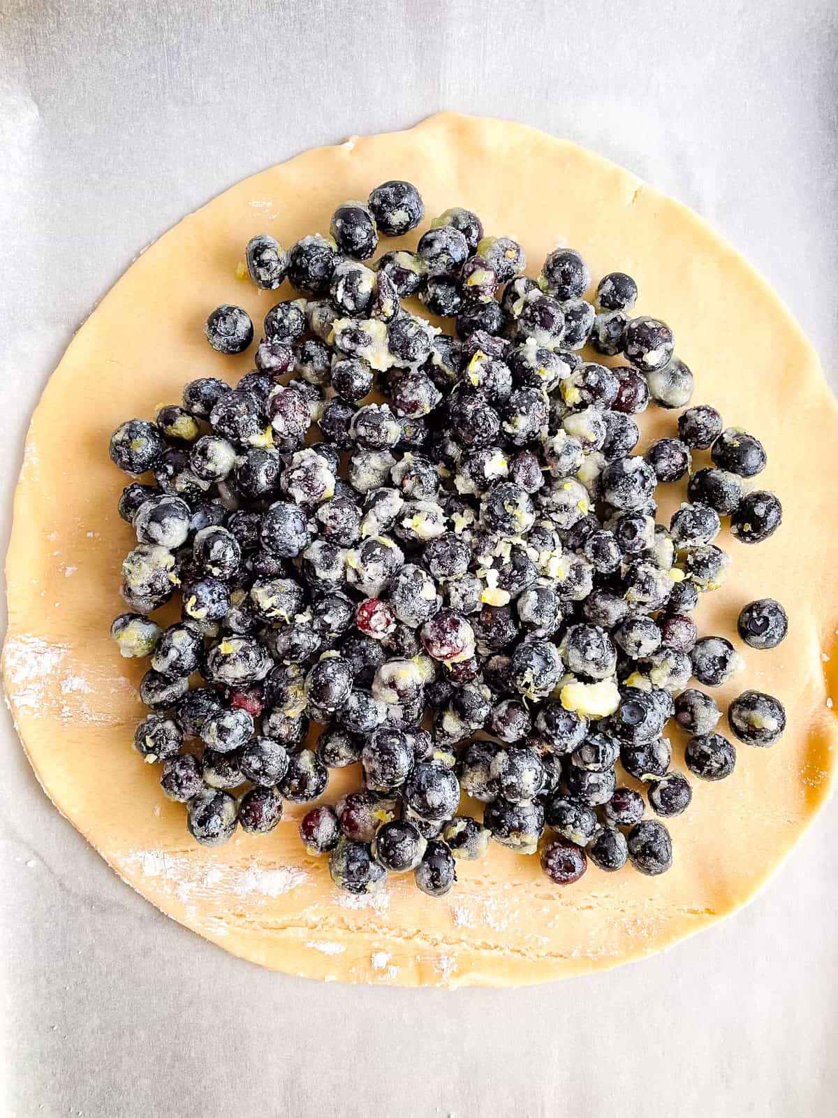 Blueberry filing sits in the center of a piece of pie dough.