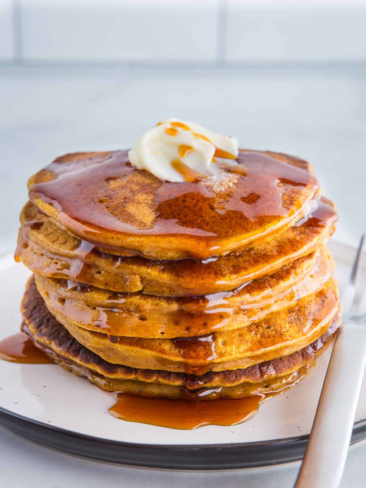 A stack of pumpkin pancakes topped with butter and syrup.
