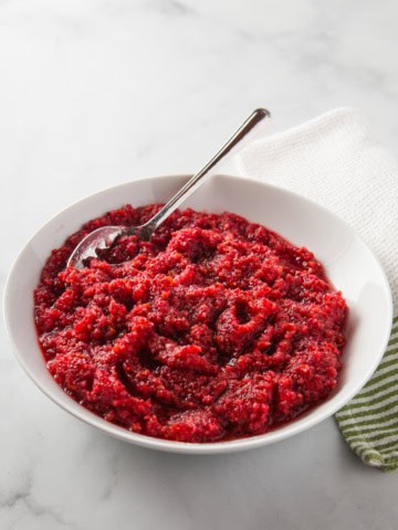 A bowl of cranberry orange relish with a spoon.