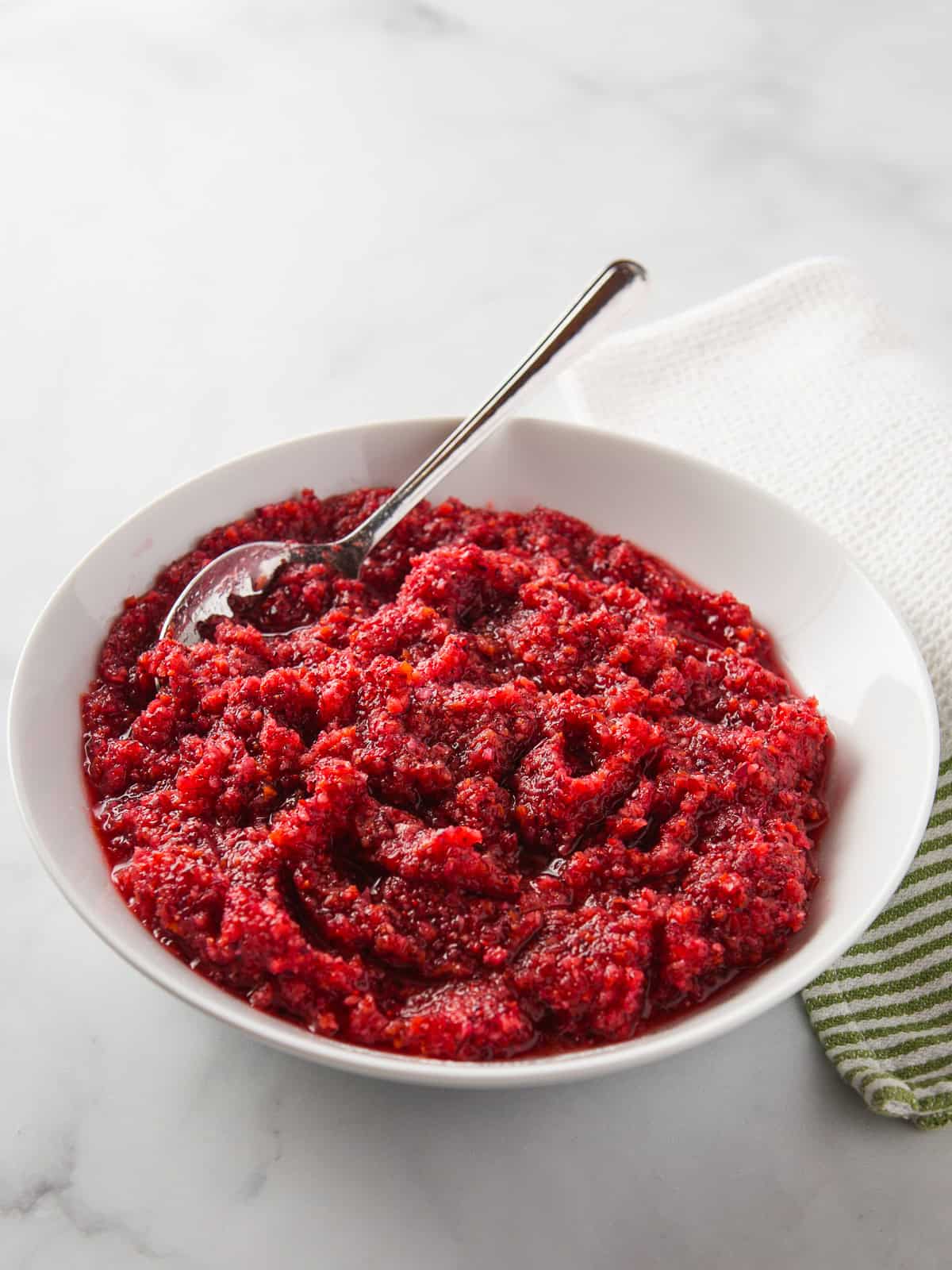 A bowl of cranberry orange relish with a spoon.