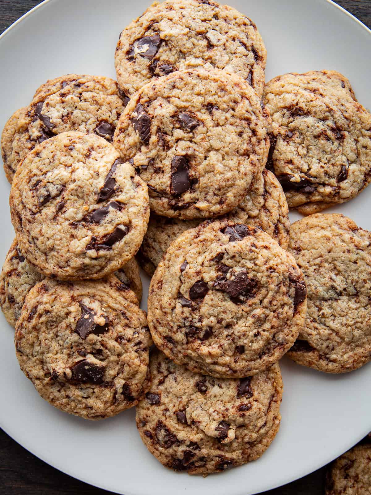 Thin chocolate chip cookies sitting on a plate.