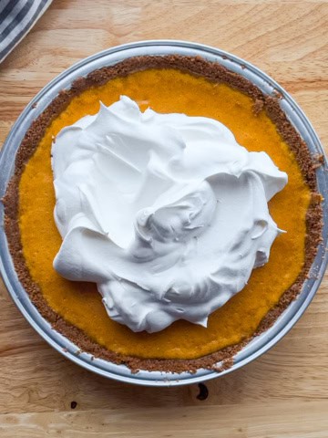 Pumpkin cheesecake pie with a gingersnap crust topped with whipped cream