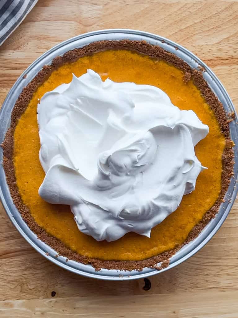 Pumpkin cheesecake pie with a gingersnap crust topped with whipped cream
